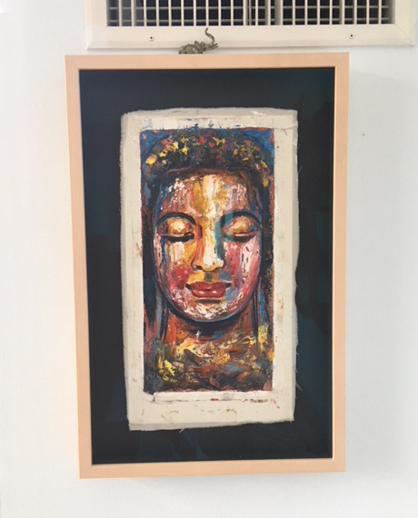 A colorful painted face artwork in a rose-gold shadow-box frame