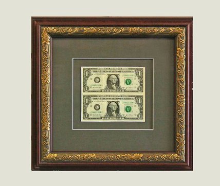 Two dollar bills framed in an ornate gold and burgundy frame